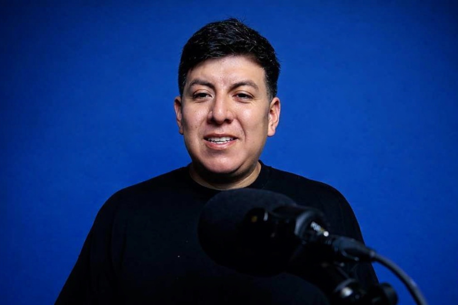 Isrrael Veliz hablando frente a un micrófono de podcast